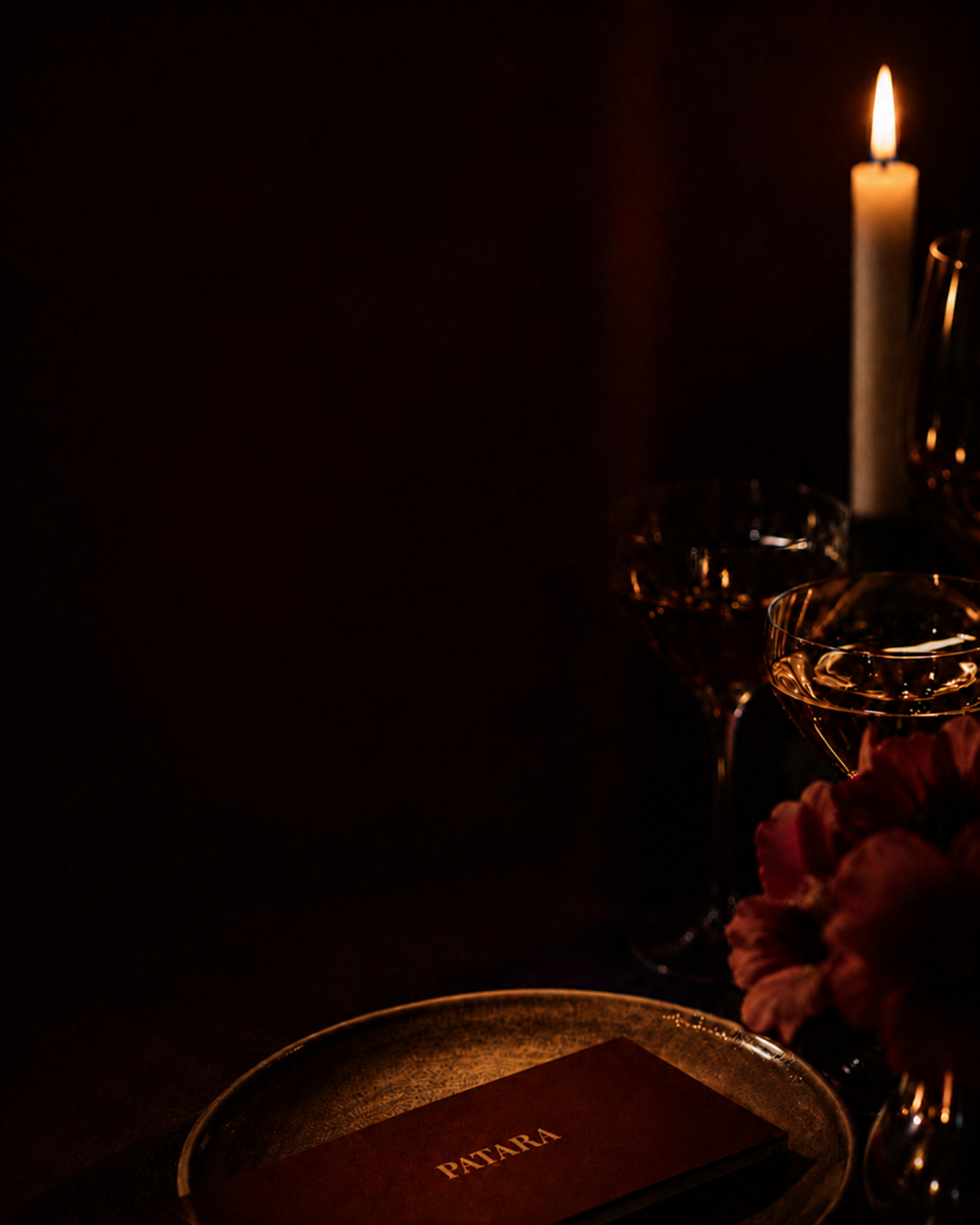 Candlelit table with coupe glasses and a Patara menu on a brass tray